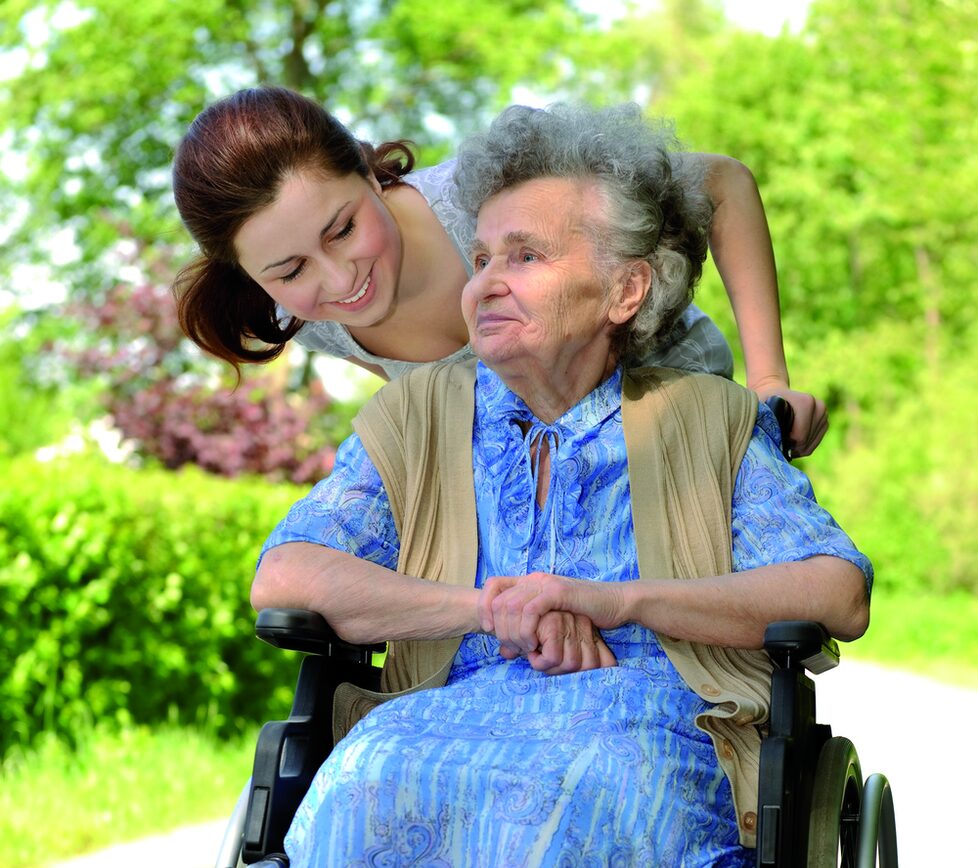Seniorin im Rollstuhl mit Betreuung