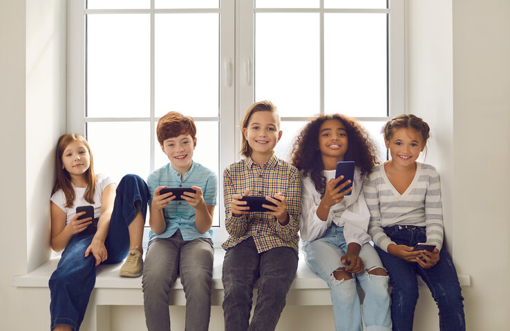 fröhliche Kinder spielen auf ihren Smartphones