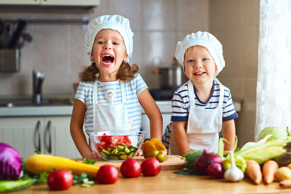 Healthy eating. Happy children prepares  vegetable salad in kitchen