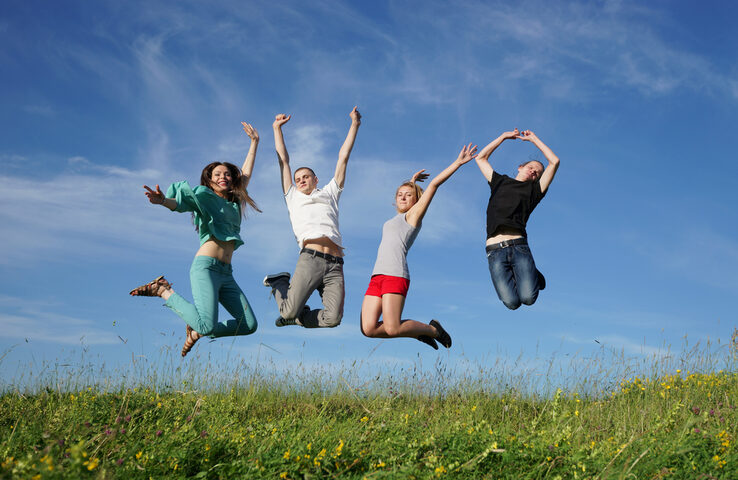 Foto Jugendliche springen auf einer Wiese