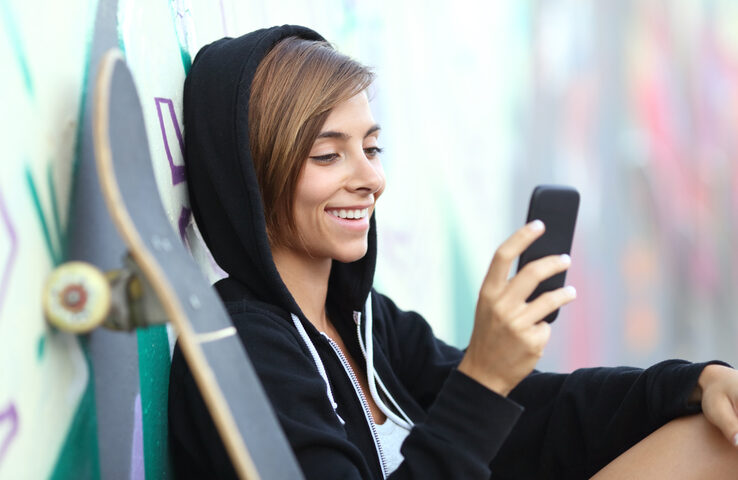 Young skater happy teen girl using a smart phone