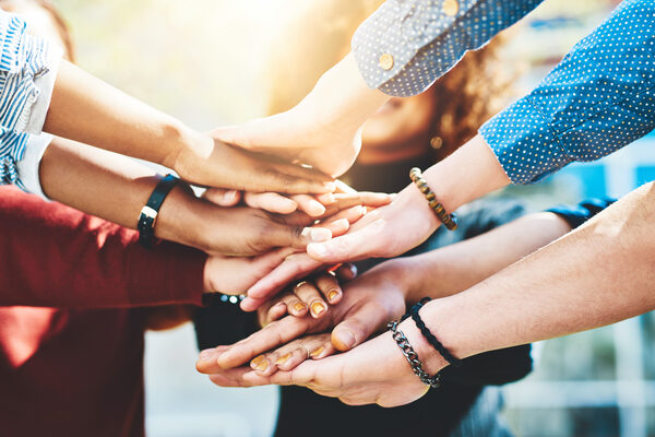 College students, closeup or stack of hands in outdoor campus meeting for group teamwork. People, lens flare or university friends in collaboration for learning together or education study at school